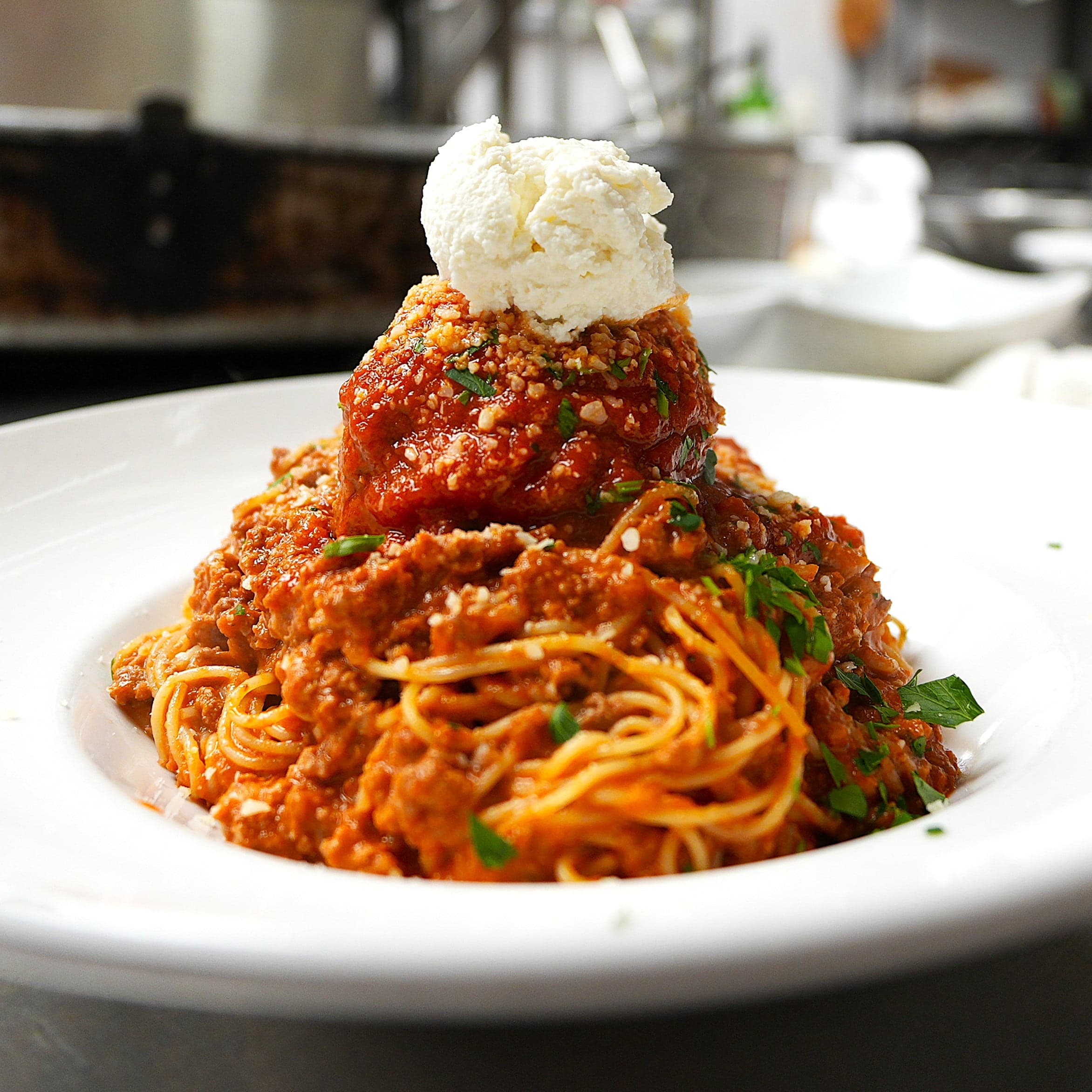 Spaghetti bolognese with a giant meatball and ricotta